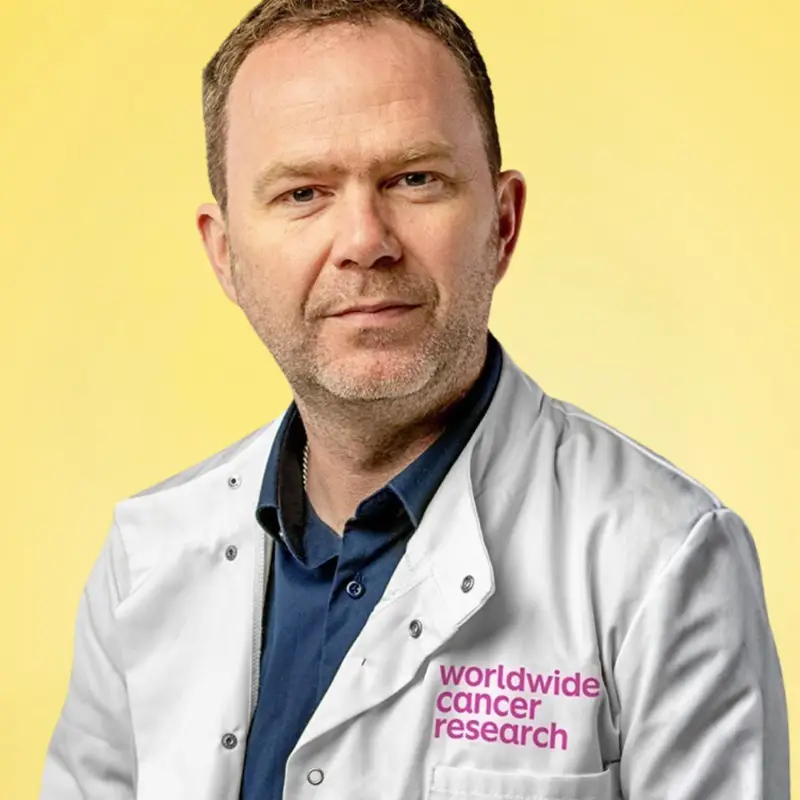 An image of Dr Niall Kenneth wearing a lab coat against a yellow background